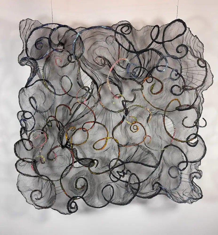 Intricate textile art with swirling black threads and colorful accents, showcasing contemporary mixed-media installation.