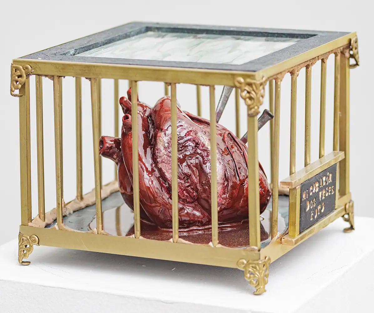 Suspended realistic heart inside vintage cage sculpture, part of Threshold Exhibition art display.